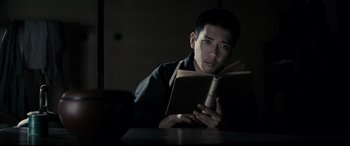 Movie still from “Letters from Iwo Jima” (2006), directed by Clint Eastwood – A man reading a book in a dark room; Close Up shot, Low angle