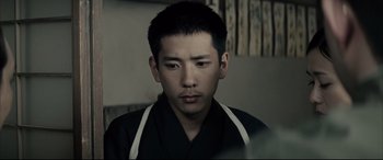 Movie still from “Letters from Iwo Jima” (2006), directed by Clint Eastwood – A man in a black shirt is looking at the camera; Close Up shot, Over the shoulder angle