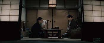 Movie still from “Letters from Iwo Jima” (2006), directed by Clint Eastwood – Two people sitting at a table with a cup of tea; Wide shot, Low angle