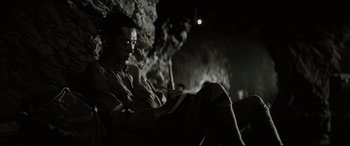 Movie still from “Letters from Iwo Jima” (2006), directed by Clint Eastwood – A man sitting in a cave reading a book; Medium shot, High angle