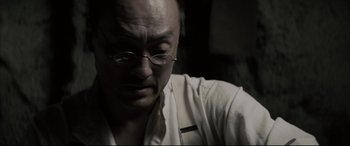 Movie still from “Letters from Iwo Jima” (2006), directed by Clint Eastwood – A man with glasses is looking down at his face; Close Up shot, Low angle