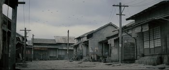 Movie still from “Letters from Iwo Jima” (2006), directed by Clint Eastwood – An old house with a bunch of birds flying overhead; Extreme Wide shot, High angle