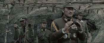 Movie still from “Letters from Iwo Jima” (2006), directed by Clint Eastwood – Two men in military uniforms standing next to each other in front of a cave; Close Up shot, Low angle