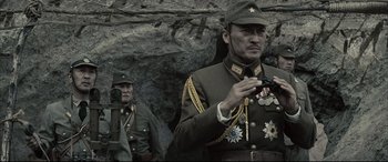 Movie still from “Letters from Iwo Jima” (2006), directed by Clint Eastwood – Two men in military uniforms are standing in front of a rock wall; Medium shot, Low angle