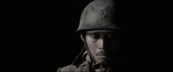 Movie still from “Letters from Iwo Jima” (2006), directed by Clint Eastwood – A man wearing a helmet is looking at the camera; Close Up shot, High angle