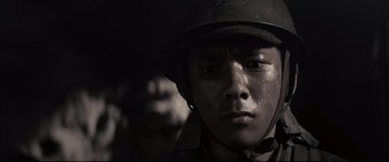 Movie still from “Letters from Iwo Jima” (2006), directed by Clint Eastwood – A man wearing a helmet is looking at the camera; Close Up shot, Low angle