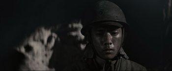 Movie still from “Letters from Iwo Jima” (2006), directed by Clint Eastwood – A man wearing a helmet in the dark with other soldiers; Close Up shot, Low angle