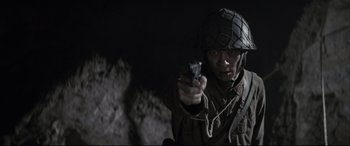 Movie still from “Letters from Iwo Jima” (2006), directed by Clint Eastwood – A man holding a cell phone while wearing a helmet; Close Up shot, Low angle