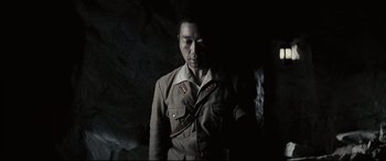 Movie still from “Letters from Iwo Jima” (2006), directed by Clint Eastwood – A man in a uniform standing in a dark cave; Medium shot, Low angle