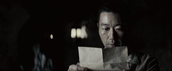 Movie still from “Letters from Iwo Jima” (2006), directed by Clint Eastwood – A man looking at a piece of paper in a dark room; Close Up shot, Over the shoulder angle