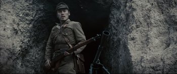 Movie still from “Letters from Iwo Jima” (2006), directed by Clint Eastwood – A man holding a rifle in front of a tree trunk; Medium shot, Low angle