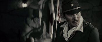 Movie still from “Letters from Iwo Jima” (2006), directed by Clint Eastwood – A man in a military uniform standing in front of flags; Close Up shot, Low angle