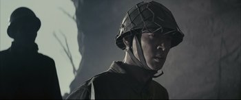 Movie still from “Letters from Iwo Jima” (2006), directed by Clint Eastwood – A man wearing a helmet is standing in the dark; Close Up shot, Low angle
