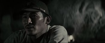 Movie still from “Letters from Iwo Jima” (2006), directed by Clint Eastwood – A person wearing a hat and ear buds; Close Up shot, Low angle