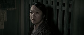 Movie still from “Letters from Iwo Jima” (2006), directed by Clint Eastwood – A woman in a striped shirt is looking at the camera; Close Up shot, Low angle