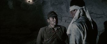 Movie still from “Letters from Iwo Jima” (2006), directed by Clint Eastwood – A man in a military uniform standing next to another man; Medium shot, Over the shoulder angle