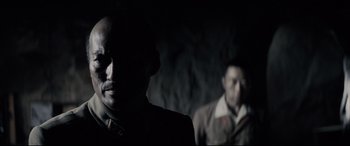 Movie still from “Letters from Iwo Jima” (2006), directed by Clint Eastwood – A man in a suit standing next to another man in a suit; Close Up shot, Over the shoulder angle