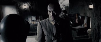 Movie still from “Letters from Iwo Jima” (2006), directed by Clint Eastwood – A man in a uniform is standing in a dark room; Close Up shot, Over the shoulder angle
