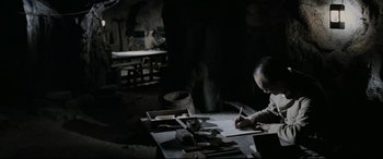 Movie still from “Letters from Iwo Jima” (2006), directed by Clint Eastwood – A man sitting at a table writing on a piece of paper; Medium shot, High angle