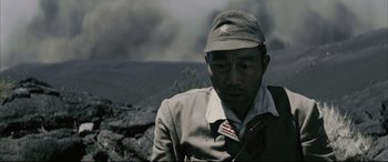 Movie still from “Letters from Iwo Jima” (2006), directed by Clint Eastwood – A man wearing a hat and a jacket in the middle of a field; Close Up shot, High angle