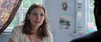 A woman standing in front of a wall with pictures on the wall