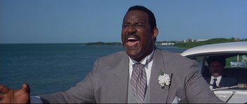 Movie still from “Licence to Kill” (1989), directed by John Glen – A man in a gray suit and a white flower on his lapel; Close Up shot, Low angle