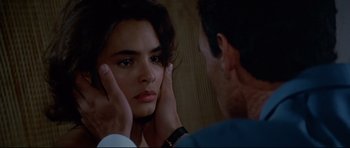 Movie still from “Licence to Kill” (1989), directed by John Glen – A woman looking in the mirror while holding her hands to her face; Close Up shot, Over the shoulder angle