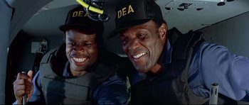 Movie still from “Licence to Kill” (1989), directed by John Glen – A couple of men sitting next to each other in a car; Close Up shot, Low angle