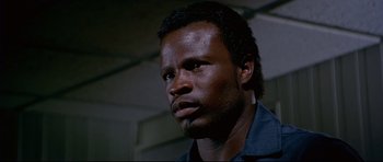 Movie still from “Licence to Kill” (1989), directed by John Glen – A person wearing a blue shirt; Close Up shot, Low angle