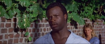 Movie still from “Licence to Kill” (1989), directed by John Glen – A person wearing a white shirt near a brick wall; Close Up shot, Low angle