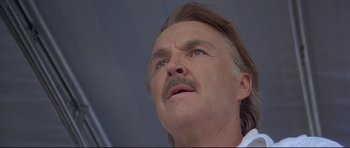 Movie still from “Licence to Kill” (1989), directed by John Glen – An older man with a mustache looking upward; Close Up shot, Low angle