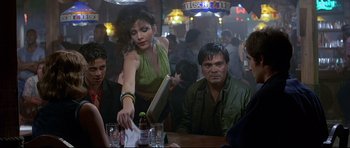 Movie still from “Licence to Kill” (1989), directed by John Glen – A group of people sitting at a table in a bar; Medium shot, Over the shoulder angle