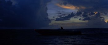 Movie still from “Licence to Kill” (1989), directed by John Glen – A man sitting on a boat in the ocean at night; Extreme Wide shot, Low angle