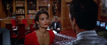 Movie still from “Licence to Kill” (1989), directed by John Glen – A woman in a red dress is talking to a man in a suit; Medium shot, Over the shoulder angle