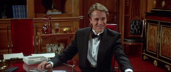 Movie still from “Licence to Kill” (1989), directed by John Glen – A man sitting at a table wearing a tuxedo; Medium shot, High angle