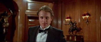 Movie still from “Licence to Kill” (1989), directed by John Glen – A man in a tuxedo standing next to a table; Close Up shot, Low angle