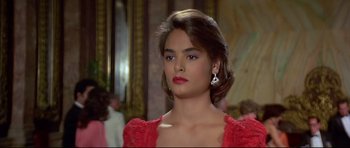 Movie still from “Licence to Kill” (1989), directed by John Glen – A woman in a red dress and silver earrings; Close Up shot, Over the shoulder angle