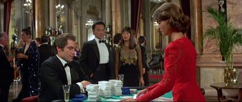 Movie still from “Licence to Kill” (1989), directed by John Glen – A group of people standing around a table with cards on it; Medium shot, Over the shoulder angle