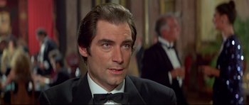 Movie still from “Licence to Kill” (1989), directed by John Glen – A man in a suit and bow tie looking to his left; Close Up shot, Over the shoulder angle