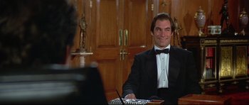 Movie still from “Licence to Kill” (1989), directed by John Glen – A man sitting at a table in front of a woman; Medium shot, High angle