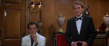 Movie still from “Licence to Kill” (1989), directed by John Glen – Two men in suits sitting next to each other in a room; Medium shot, Low angle