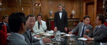 Movie still from “Licence to Kill” (1989), directed by John Glen – A group of men sitting at a table in a room; Medium shot, Over the shoulder angle