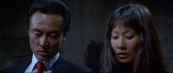 Movie still from “Licence to Kill” (1989), directed by John Glen – A man and a woman standing next to each other; Close Up shot, Low angle