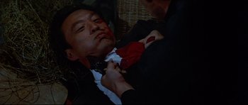 Movie still from “Licence to Kill” (1989), directed by John Glen – A man in a black suit and a red neck tie; Close Up shot, High angle
