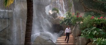 Movie still from “Licence to Kill” (1989), directed by John Glen – A man walking down a set of stairs next to a waterfall; Wide shot, High angle