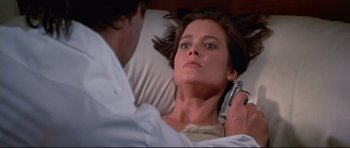 Movie still from “Licence to Kill” (1989), directed by John Glen – A woman laying in a bed with a cell phone in front of her face; Close Up shot, Overhead angle