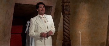 Movie still from “Licence to Kill” (1989), directed by John Glen – A man in a white suit standing in front of a pillar; Medium shot, Low angle