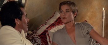 Movie still from “Licence to Kill” (1989), directed by John Glen – A woman sitting in front of a pillow; Close Up shot, Over the shoulder angle