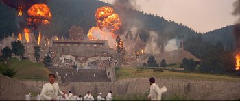 Movie still from “Licence to Kill” (1989), directed by John Glen – A group of people standing in front of a burning building; Extreme Wide shot, High angle
