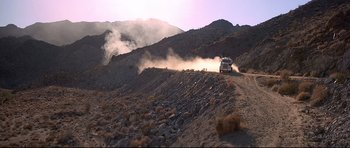 Movie still from “Licence to Kill” (1989), directed by John Glen – A car driving down a dirt road on a hill; Extreme Wide shot, Low angle